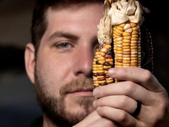 a young man holds up Catawba indigenous corn