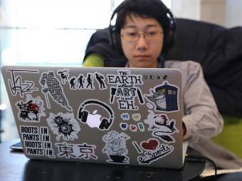 Student types at laptop while wearing headphones