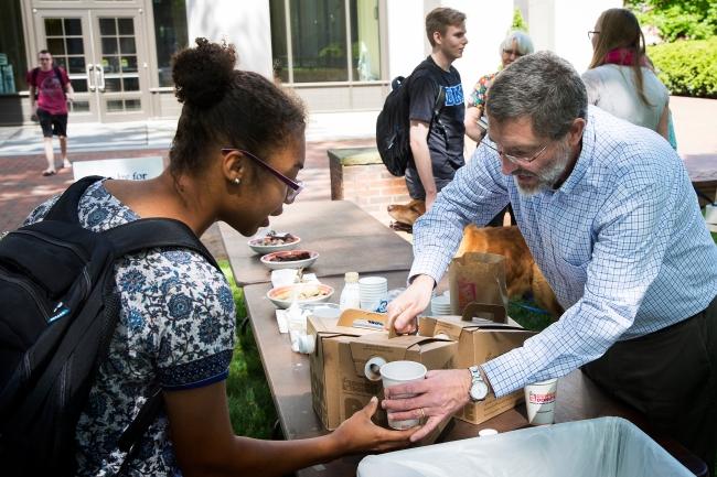 Chaplain Rob Spach serves coffee to student in the sculpture garden