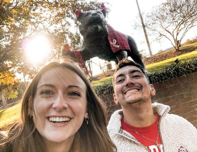 two students smiling in front of wildcat statue