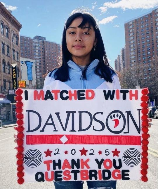 Student holding sign that says "I matched with Davidson - thank you QuestBridge"