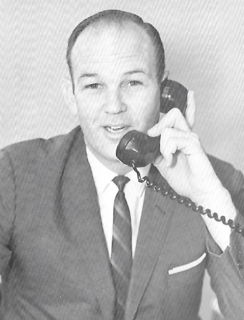a black and white photo of a man holding a phone in a suit
