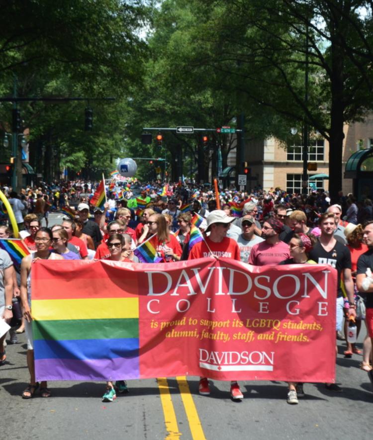 Davidson people hold up a banner that says the college supports LGBTQ members of the community during Pride