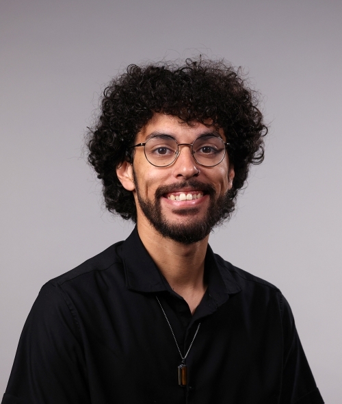 a man with curly dark hair wearing glasses and a black shirt