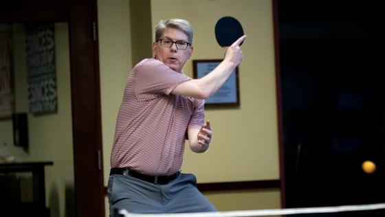 A white male hits a ping pong ball with a paddle
