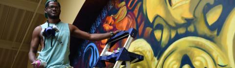 Stewy Robertson '15 with can of spray paint, working on mural