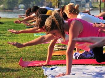 Students take yoga positions on mats laid out on the grass of Lake Campus