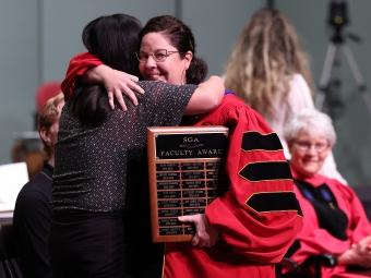 Two people hugging onstage at Convocation