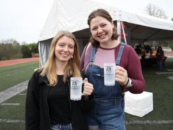 Two students holding plastic cups of water and smiling