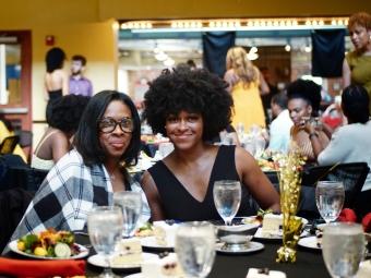 a young Black woman and an older Black woman sit together a table