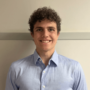 a young white man with curly brown hair wearing a blue collared shirt