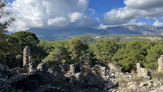 an ancient amphitheater with mountains and blue skies in the background