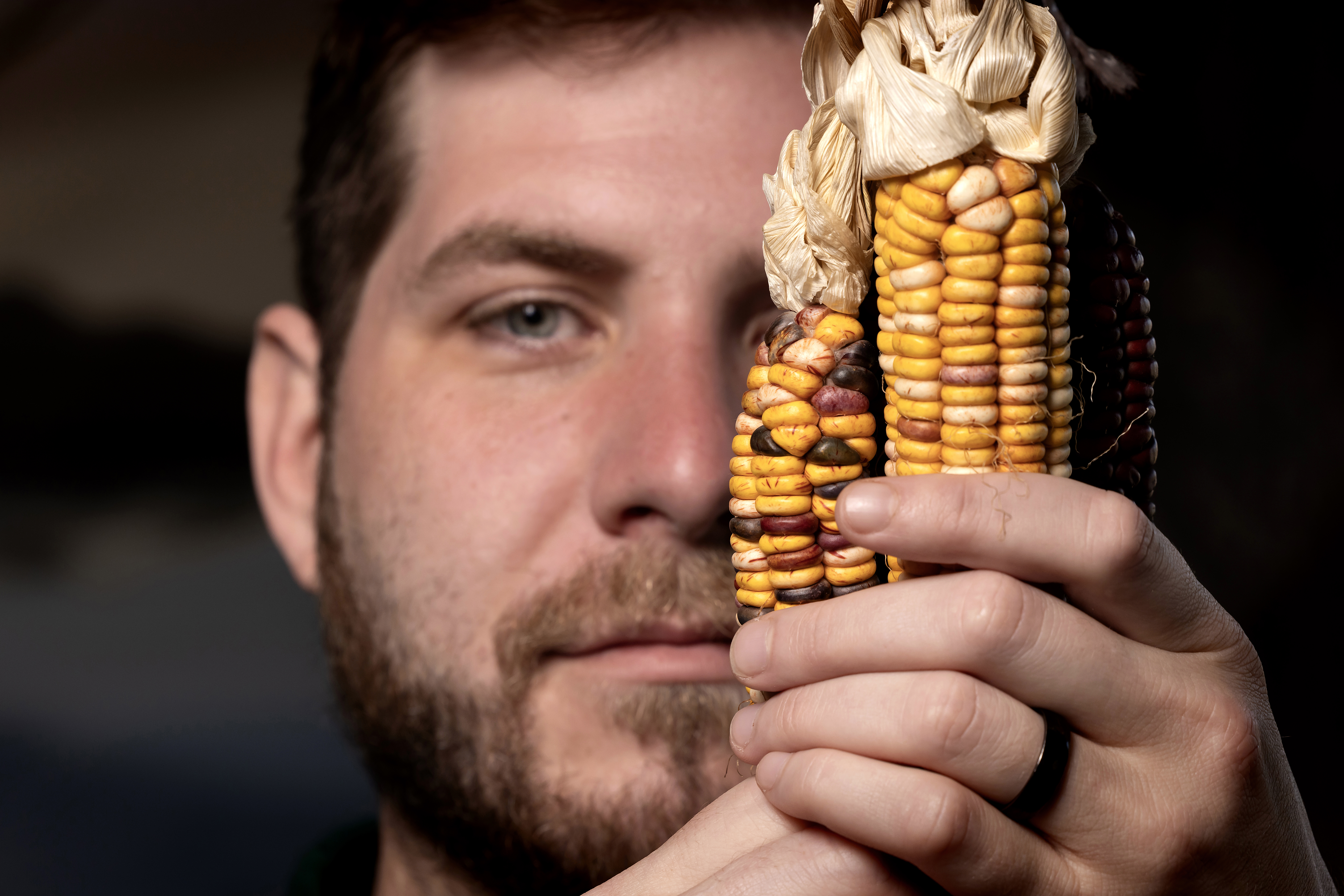 a young man holds up Catawba indigenous corn