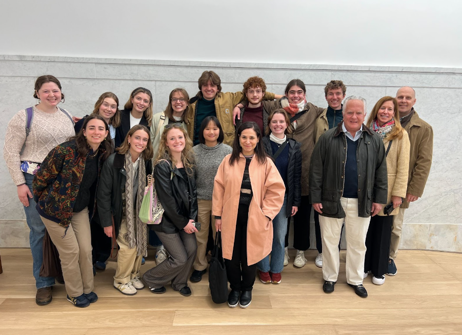 a group of students and a few adults stand together in an art gallery