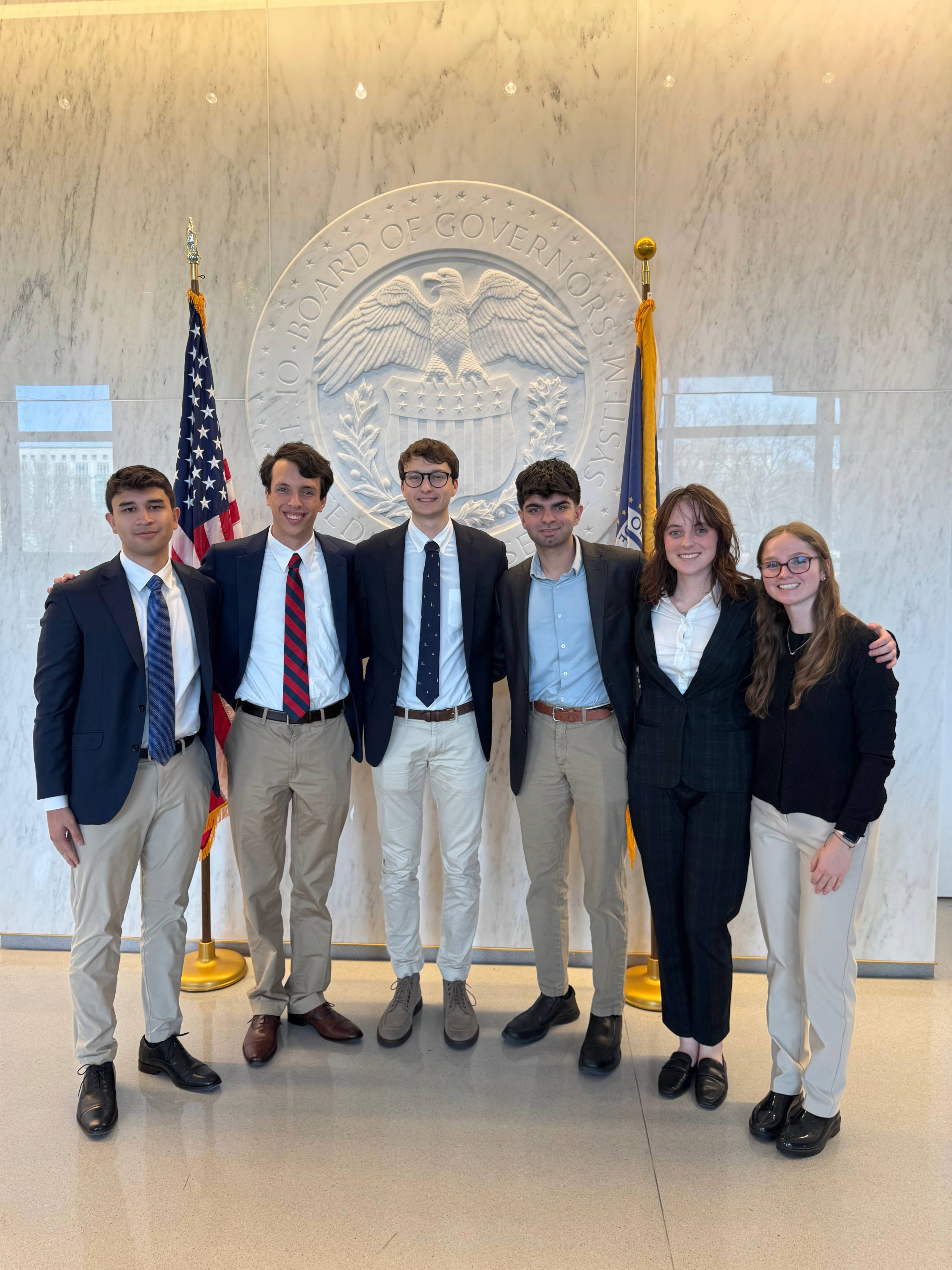 a group of six young people standing in front of the federal reserve building
