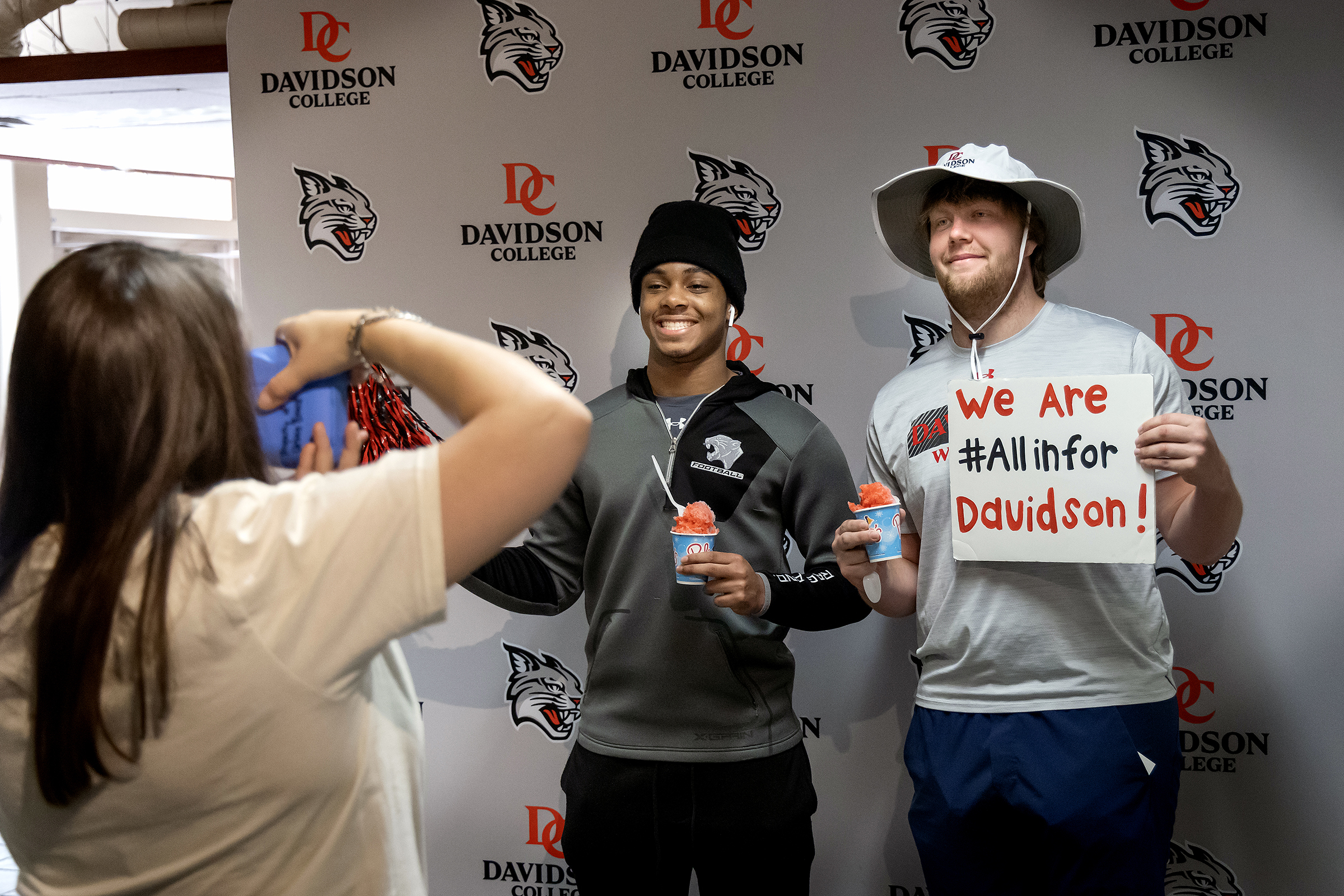 Two students pose with sno-cones and Davidson-themed signs at All In for Davidson