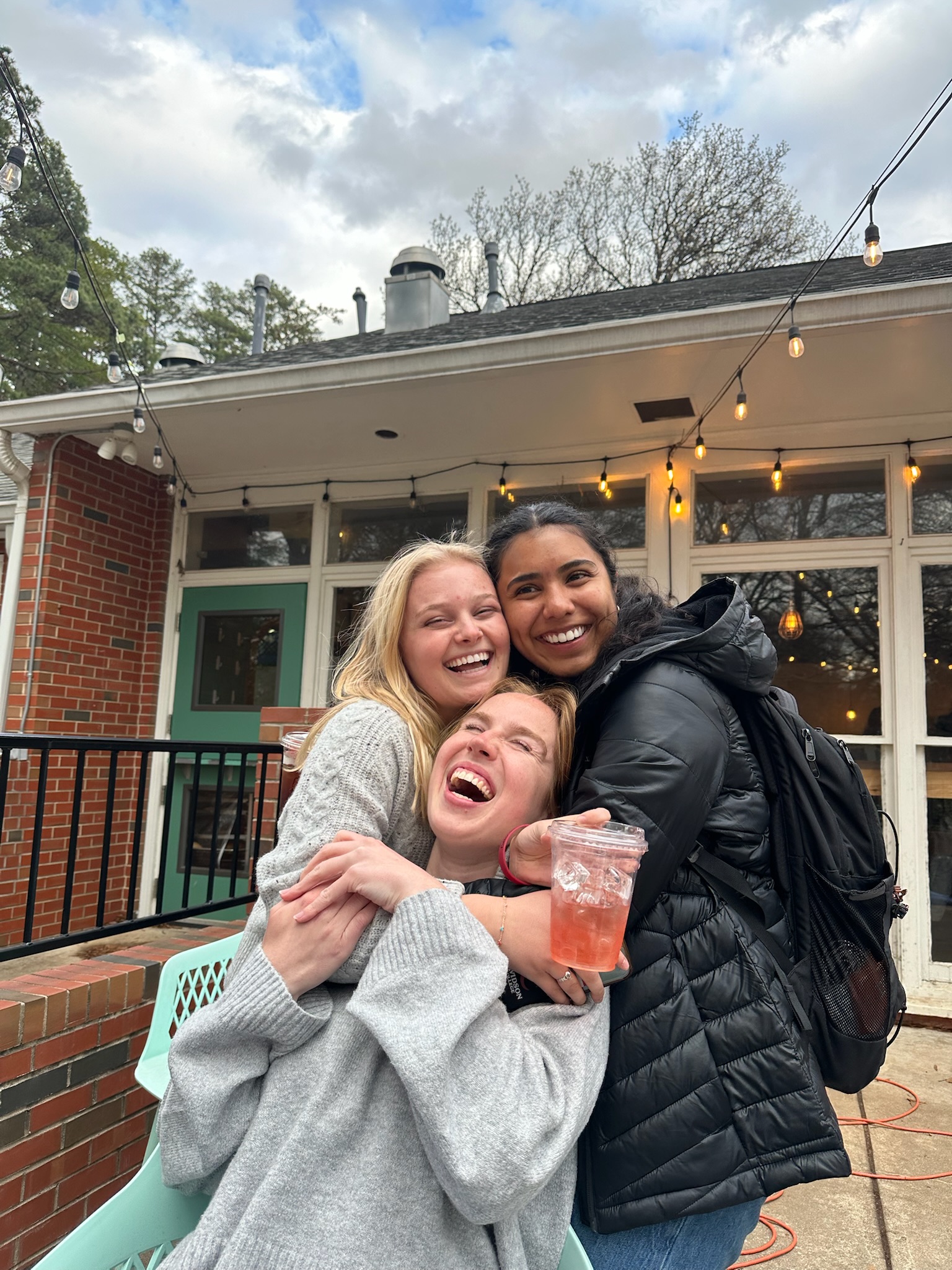 a group of young women smiling and holding a coffee