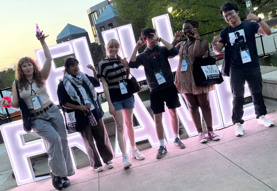 a group of young people smile and pose in front of a sign that reads "Full Frame"