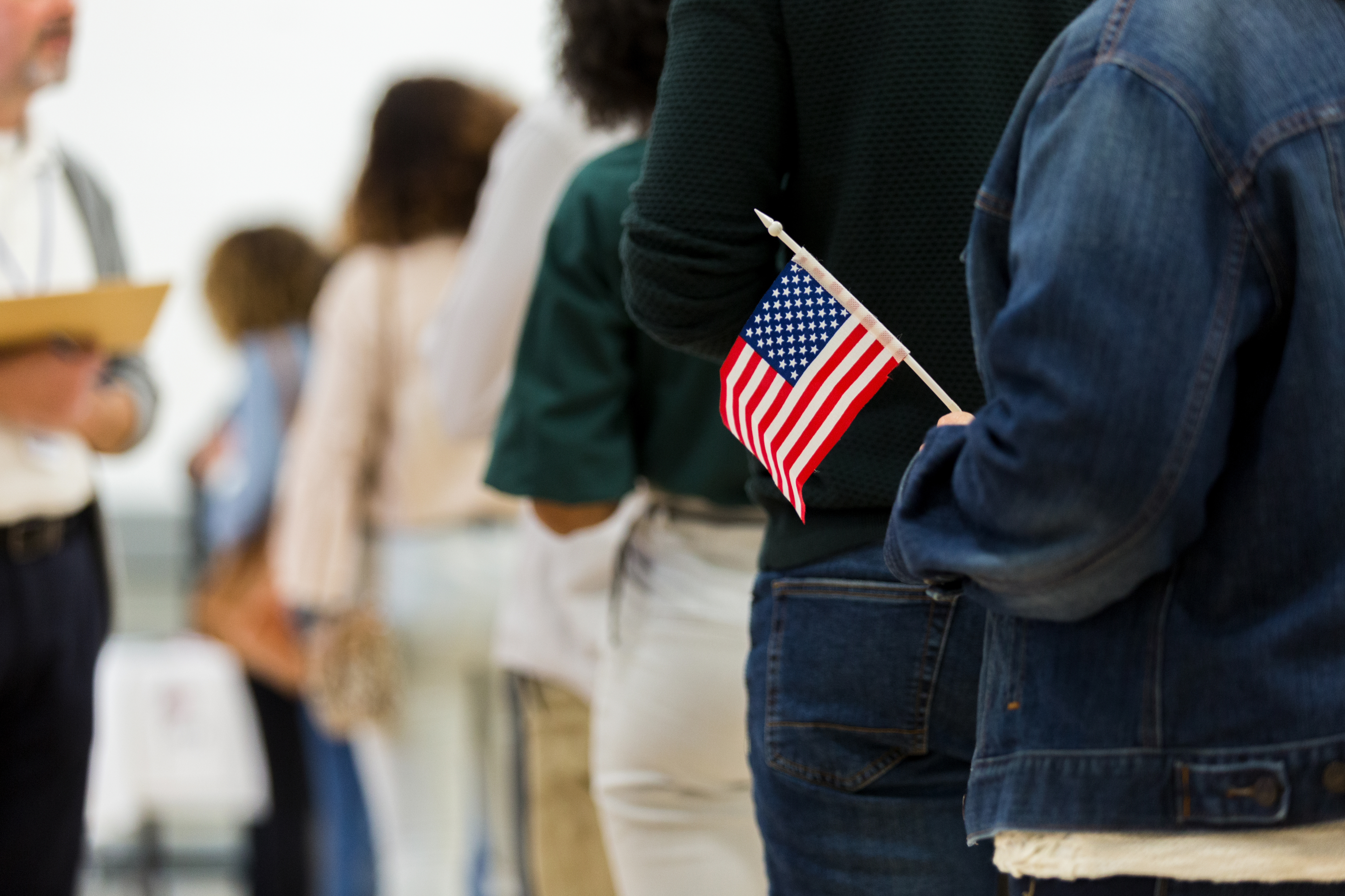 Person in line to vote holding American flag
