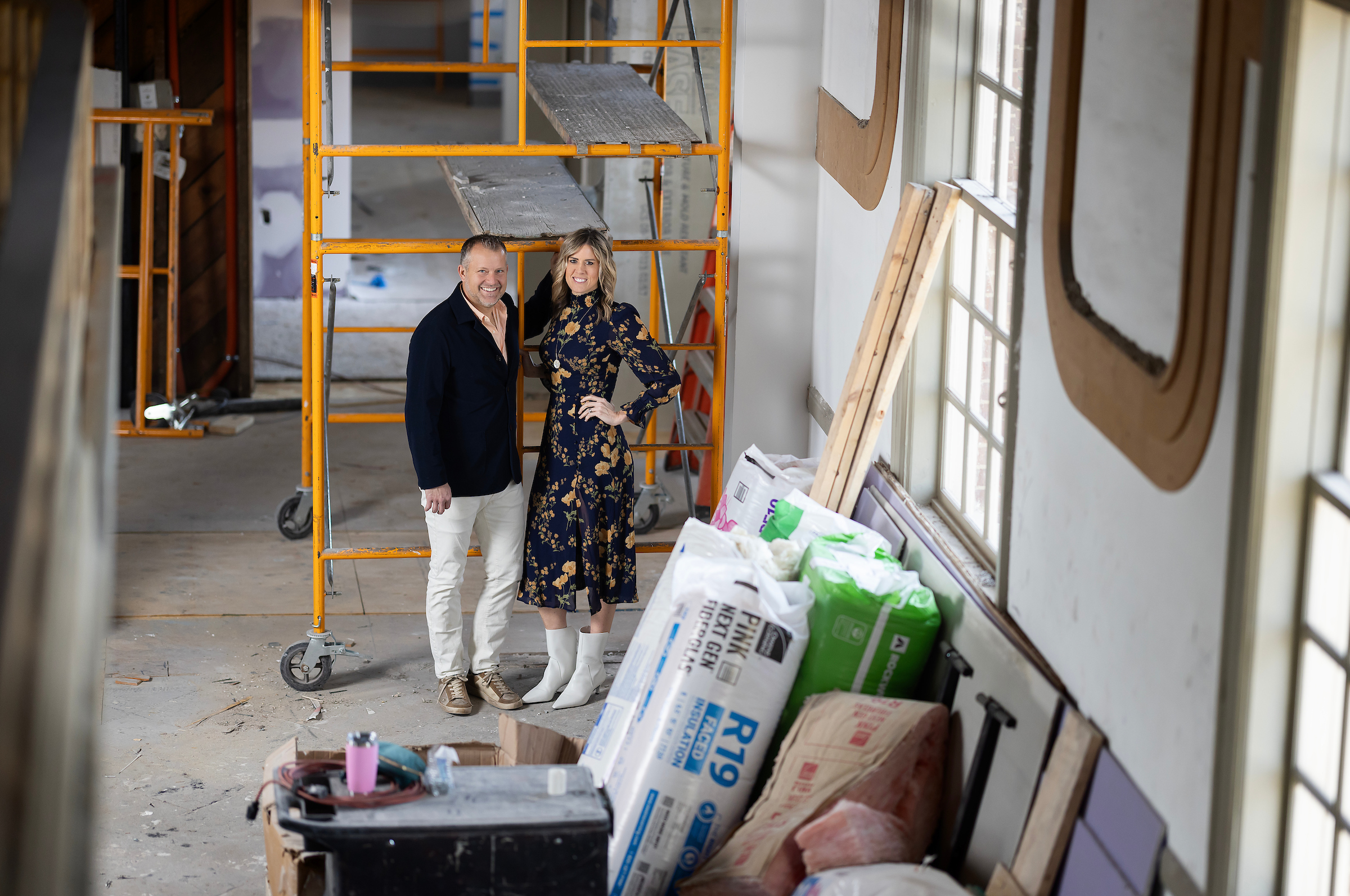 a young white couple stand together in a church under renovation