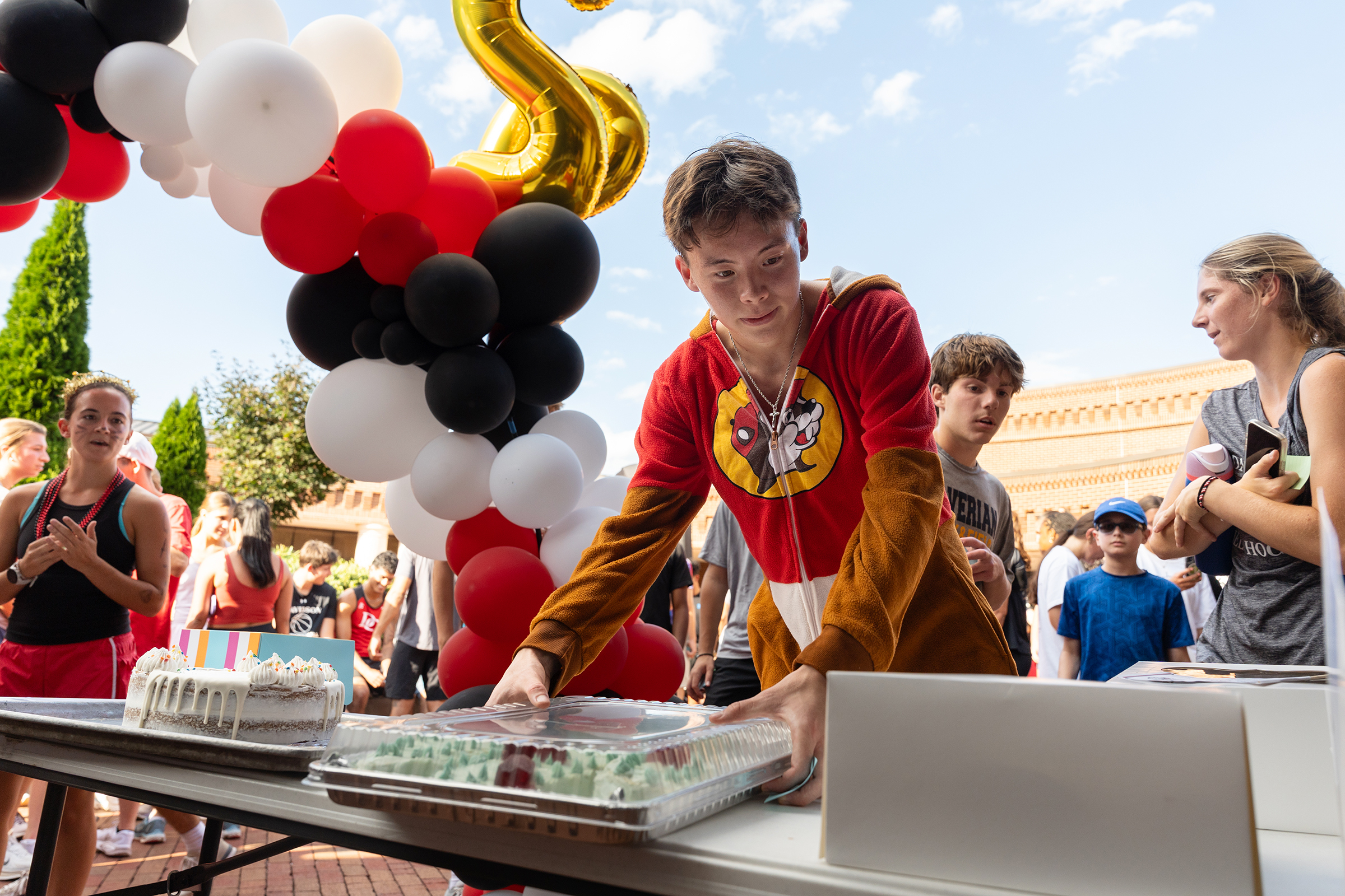 Student in Buc-ees pajama onesie picks a cake after finishing the race
