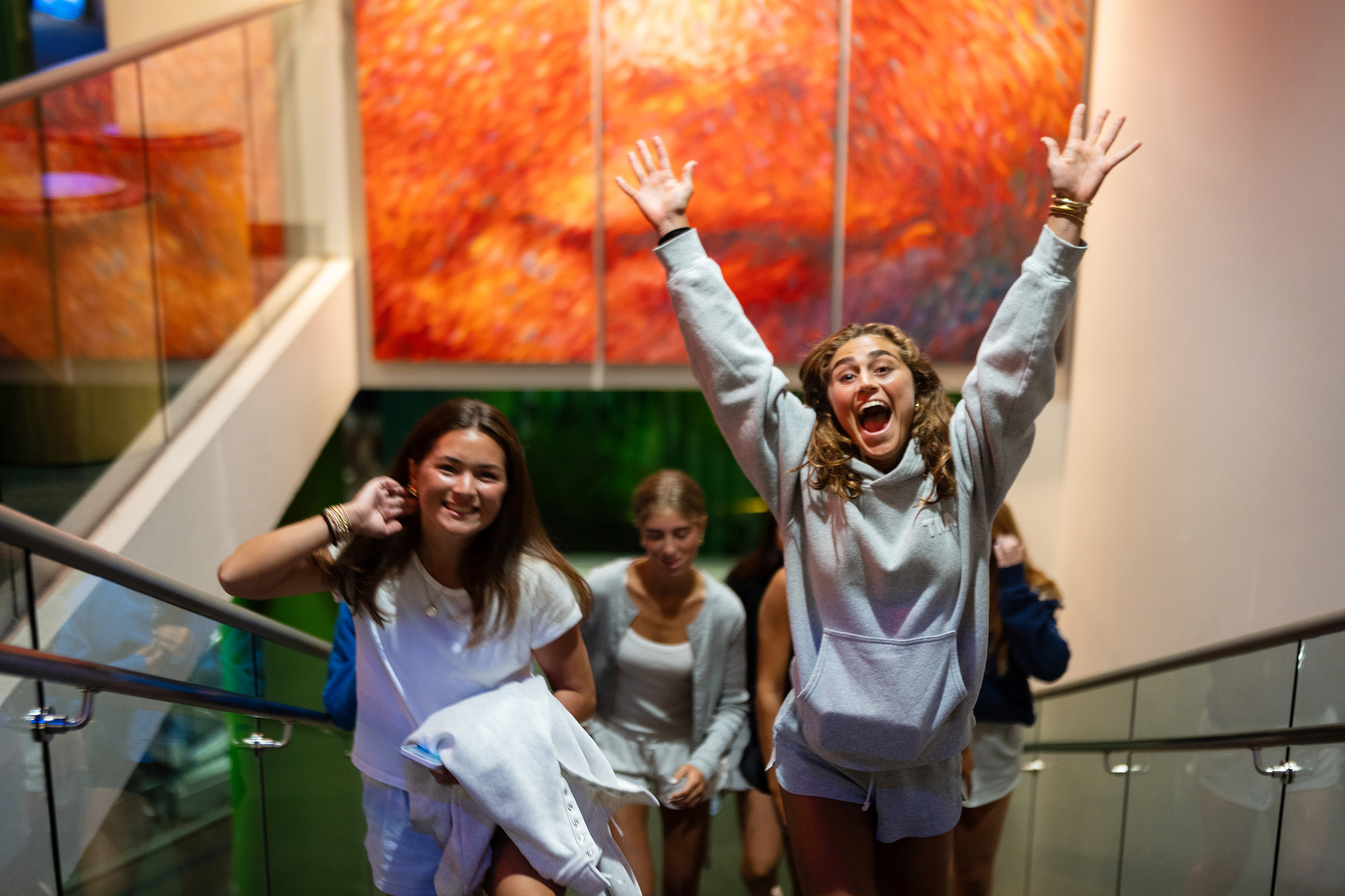 young women jump and smile in a museum