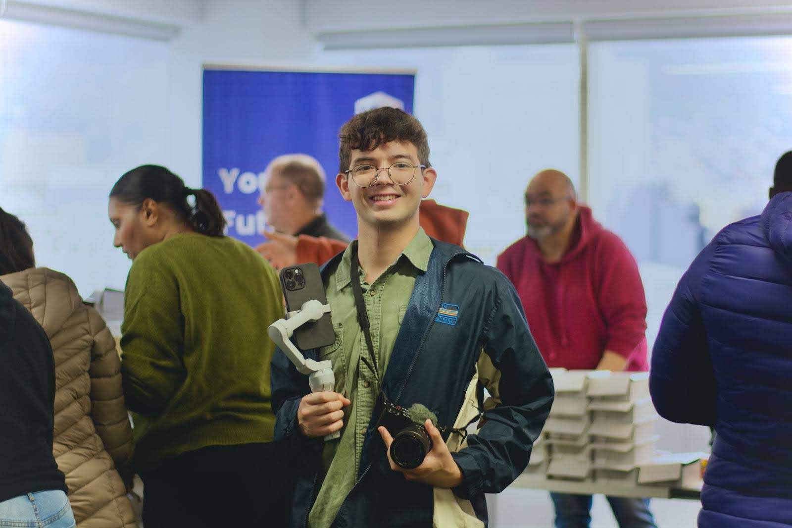 a young man with a camera and phone works media at an event