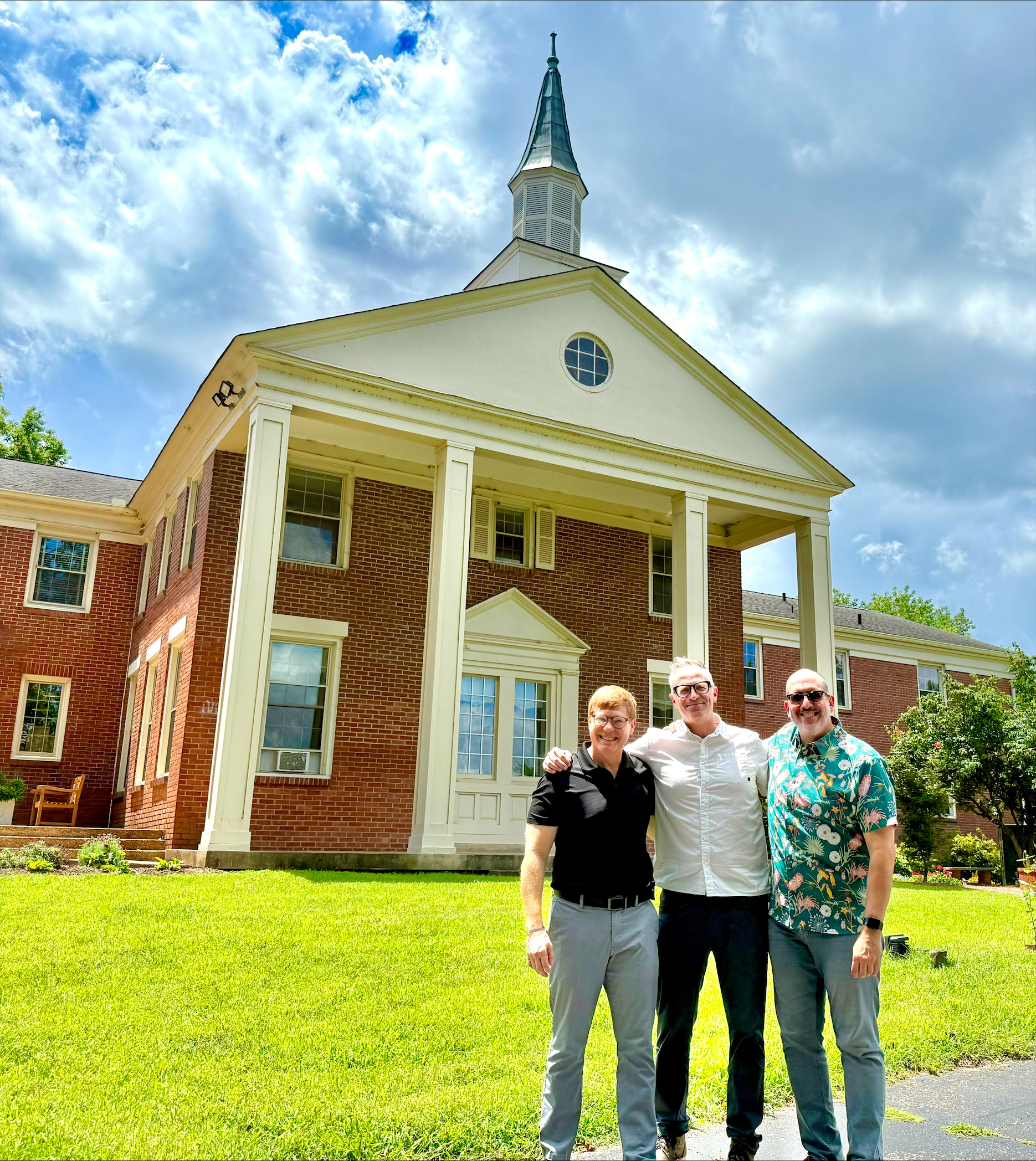 a group of three professors in front of a church on a sunny day