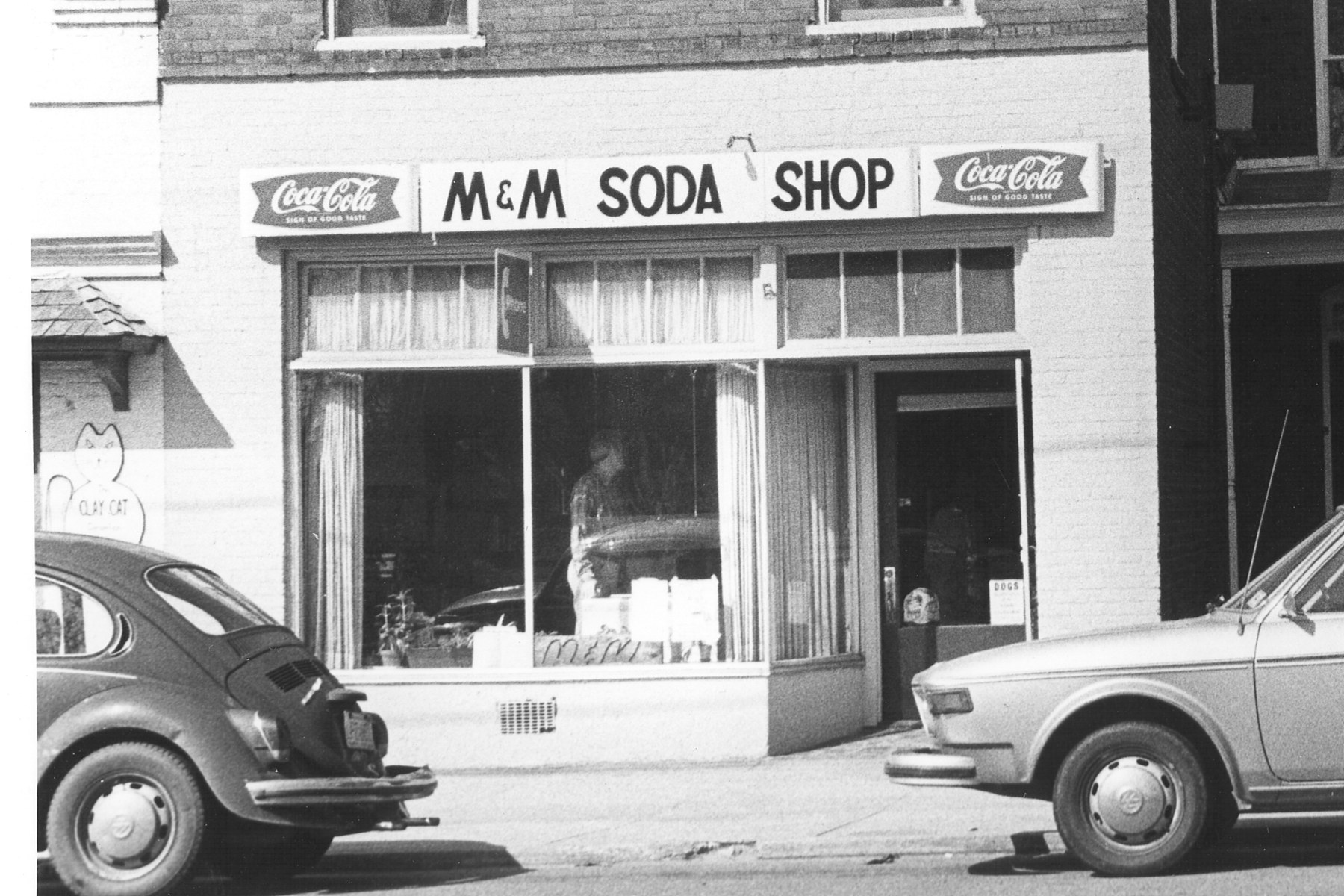 Then: the M&M Soda Shop storefront in the 1970s, with a Volkswagen Beetle parked out front