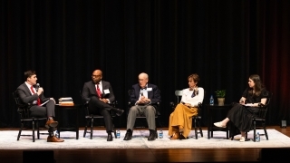 a young man speaks to a panel of alumni on a stage