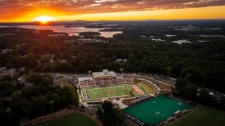 an aerial view of a football stadium as the sun sets in the distance over a lake