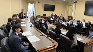 a group of young people sit around in a room working together