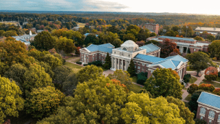 an aerial view of a college campus with brick buildings, green trees and a lake in the distance