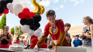 Student in Buc-ees pajama onesie picks a cake after finishing the race