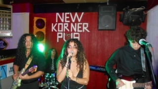 A group of students stand on a dimly lit stage with instruments