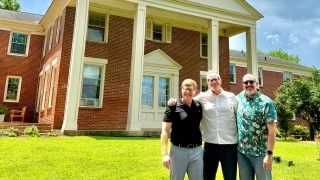 a group of three professors in front of a church on a sunny day