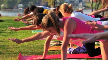 Students take yoga positions on mats laid out on the grass of Lake Campus