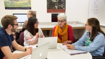 Prof. Munger sits at a round table with three students in her lab