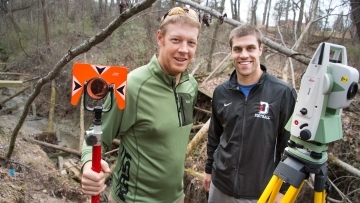 Prof. Brad Johnson and student stand in field with research equipment  