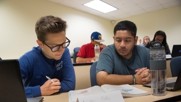 Two students sit next to one another and analyze a text