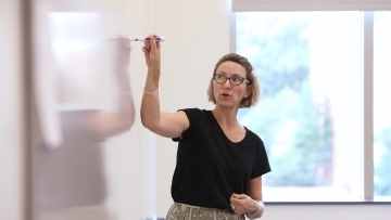Anne Wills teaches class and writes on white board