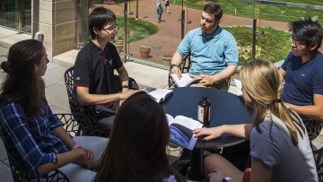 a group of students sit around a table discussing a text