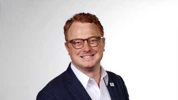 a young white man with red hair wearing glasses