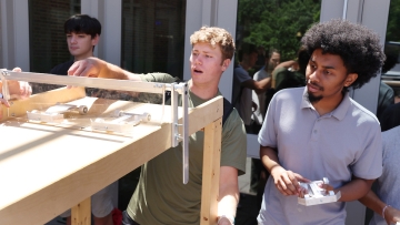 a group of young men race miniature cars outdoors