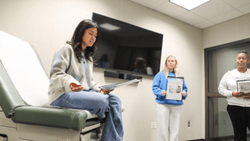 a young woman sits in a hospital room