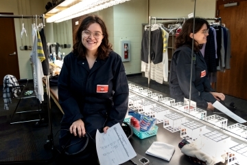 a young woman smiles while standing in a dressing room in front of a mirror