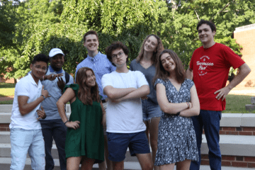 a group of students making silly faces while standing on stone steps outside