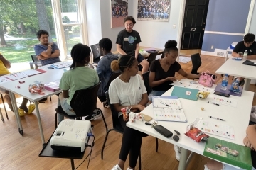 a group of young people in a classroom working at tables together