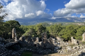 an ancient amphitheater with mountains and blue skies in the background