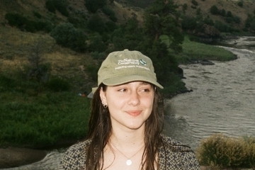 a young white woman smiling wearing a baseball cap
